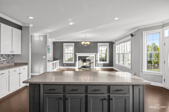 kitchen featuring a wealth of natural light, a fireplace, white cabinets, and dark wood-type flooring