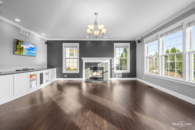 unfurnished living room with a high end fireplace, hardwood / wood-style flooring, crown molding, and a notable chandelier