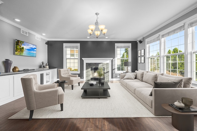 living room with a premium fireplace, an inviting chandelier, ornamental molding, and hardwood / wood-style flooring