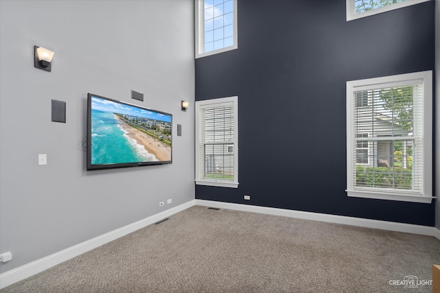 carpeted spare room featuring a towering ceiling