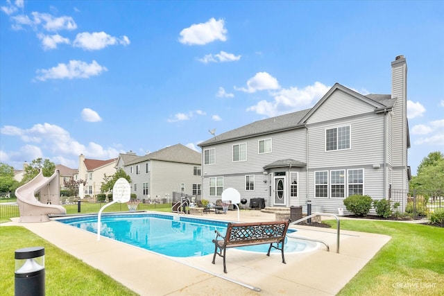 rear view of property with a patio area, a yard, and a fenced in pool