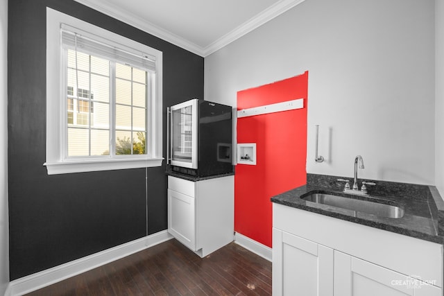 kitchen with dark hardwood / wood-style flooring, dark stone counters, crown molding, sink, and white cabinetry