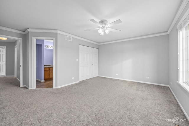 unfurnished bedroom featuring ensuite bathroom, crown molding, ceiling fan, carpet floors, and a closet