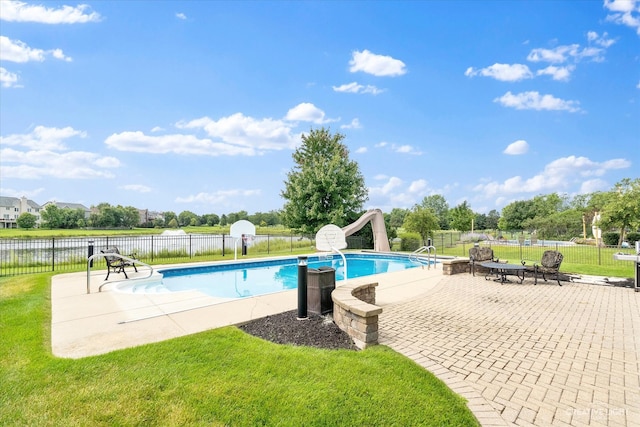 view of pool featuring a yard, a water view, a patio area, and a water slide