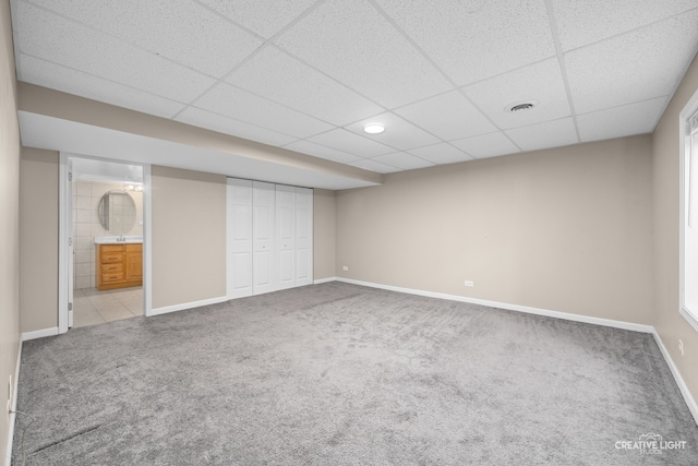 unfurnished bedroom with light carpet, a paneled ceiling, ensuite bath, and a closet