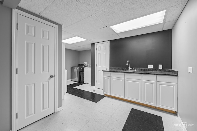 kitchen featuring white cabinets, a drop ceiling, separate washer and dryer, and sink