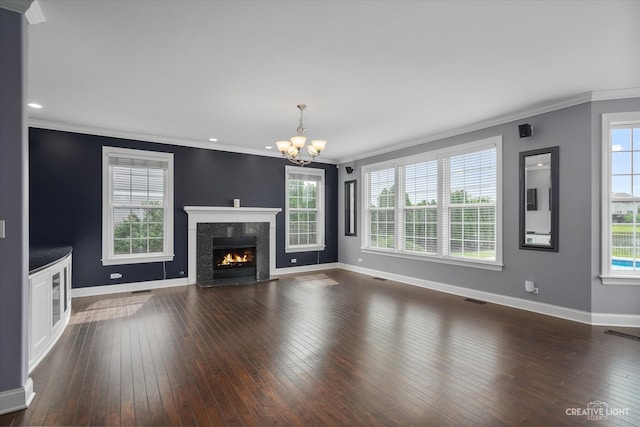 unfurnished living room featuring dark hardwood / wood-style floors, a healthy amount of sunlight, crown molding, and an inviting chandelier