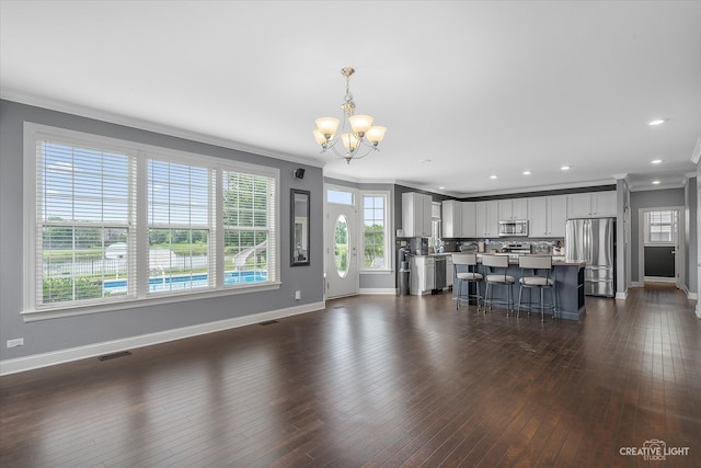 unfurnished living room featuring a chandelier, dark hardwood / wood-style floors, and ornamental molding