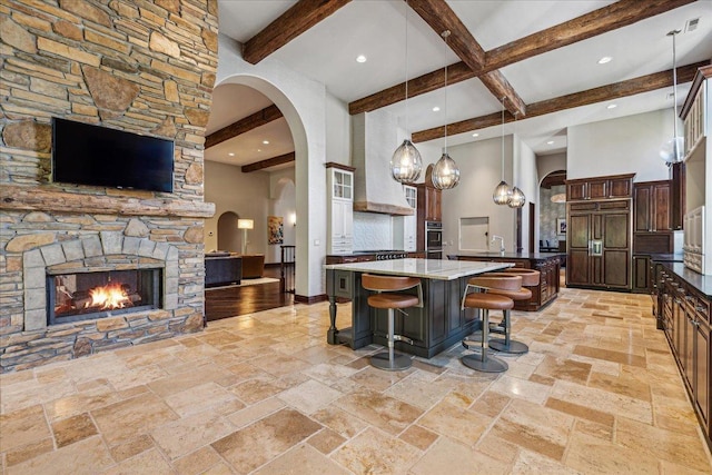 kitchen featuring a kitchen bar, a spacious island, open floor plan, paneled built in fridge, and arched walkways