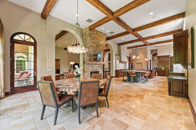 dining room featuring visible vents, beam ceiling, stone tile flooring, arched walkways, and a towering ceiling