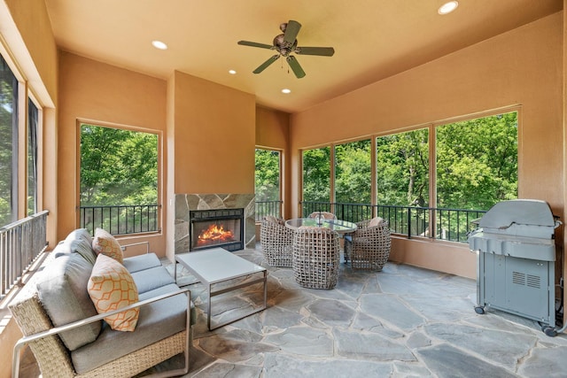 sunroom / solarium featuring a tiled fireplace and a ceiling fan