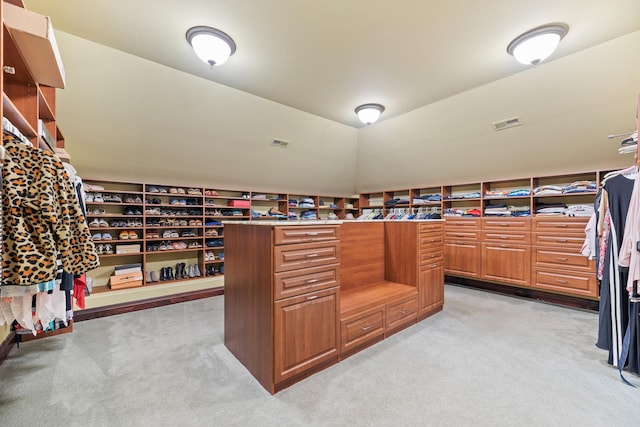 walk in closet featuring vaulted ceiling, light colored carpet, and visible vents
