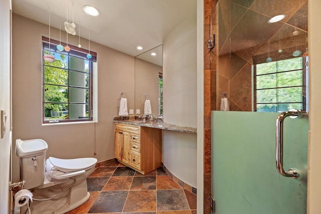bathroom with stone tile floors, a stall shower, toilet, and vanity