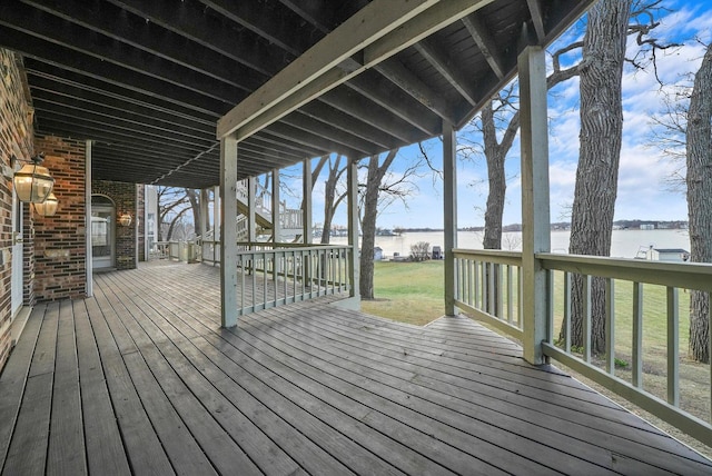 wooden deck featuring a lawn and a water view