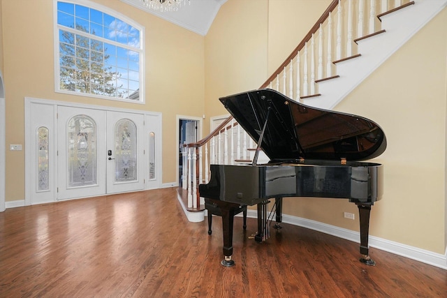 entryway with french doors, a towering ceiling, ornamental molding, and wood-type flooring