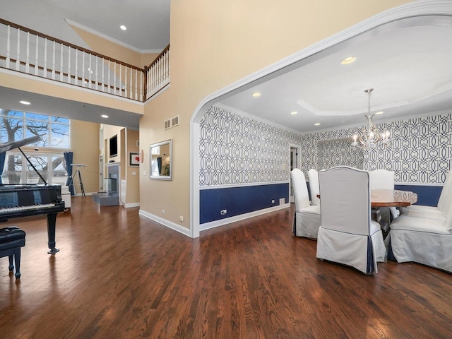 dining area with dark hardwood / wood-style flooring, ornamental molding, a high ceiling, and an inviting chandelier