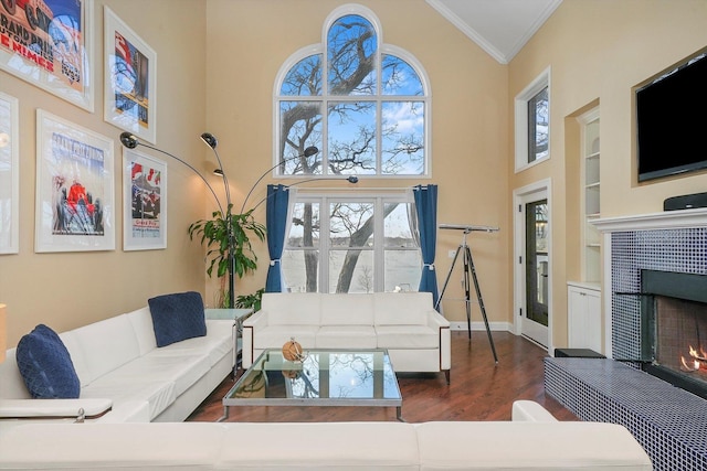 living room featuring built in shelves, dark hardwood / wood-style floors, ornamental molding, and a high ceiling