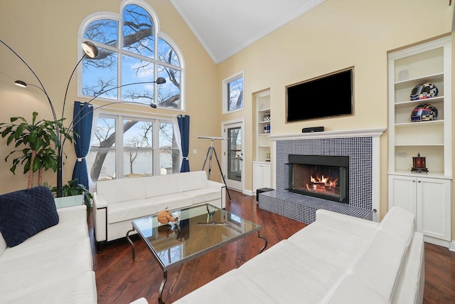 living room featuring high vaulted ceiling, crown molding, built in features, a fireplace, and dark hardwood / wood-style flooring