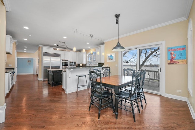 dining space featuring dark hardwood / wood-style flooring, rail lighting, and ornamental molding