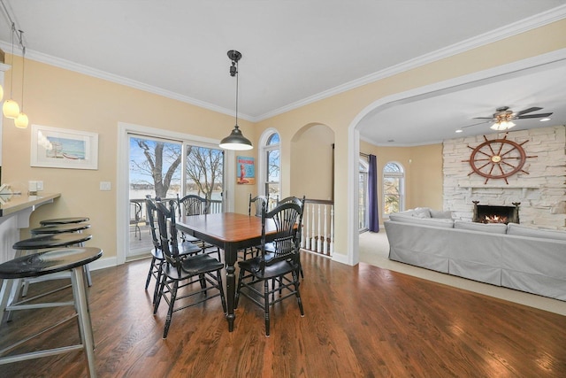 dining area featuring crown molding, a fireplace, ceiling fan, and dark hardwood / wood-style floors