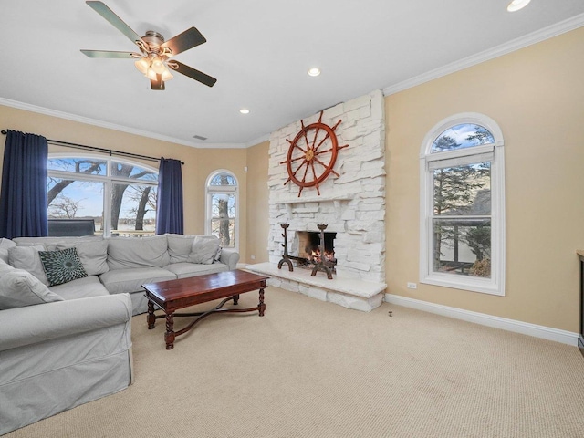 carpeted living room featuring a wealth of natural light, a fireplace, ceiling fan, and crown molding