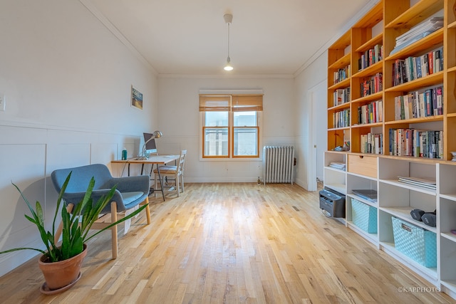 sitting room featuring light wood-type flooring, radiator heating unit, and crown molding