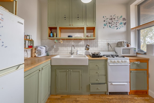 kitchen featuring green cabinetry, decorative backsplash, white appliances, and light wood-type flooring