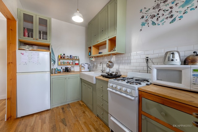 kitchen with tasteful backsplash, light hardwood / wood-style flooring, decorative light fixtures, white appliances, and green cabinetry