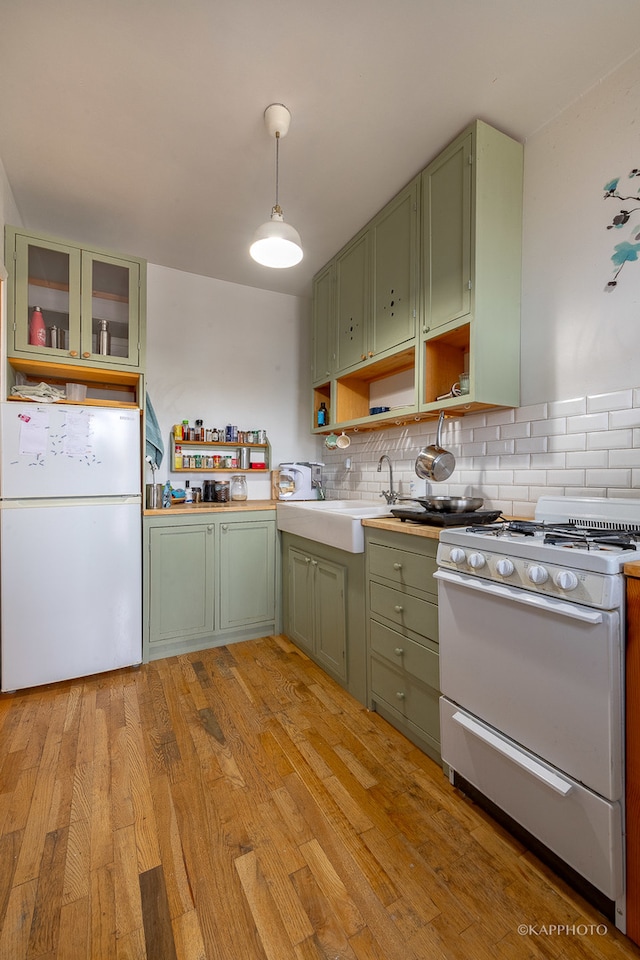 kitchen featuring light wood-type flooring, pendant lighting, white appliances, and green cabinetry