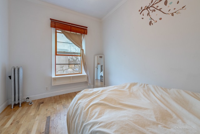 bedroom featuring radiator heating unit, ornamental molding, and light hardwood / wood-style flooring