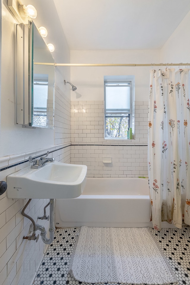 bathroom with tile patterned flooring, shower / tub combo, tile walls, and sink