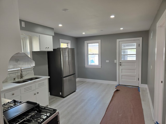 kitchen featuring sink, white cabinetry, stainless steel appliances, and light wood-type flooring