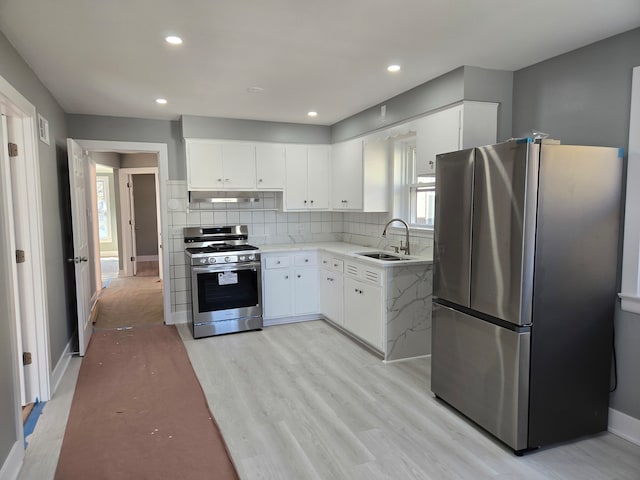 kitchen featuring white cabinetry, sink, light hardwood / wood-style floors, and appliances with stainless steel finishes