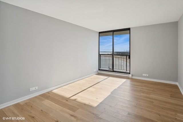 unfurnished room featuring wood-type flooring and expansive windows