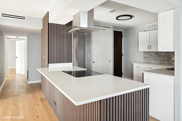 kitchen with black electric stovetop, a center island, white cabinets, and range hood