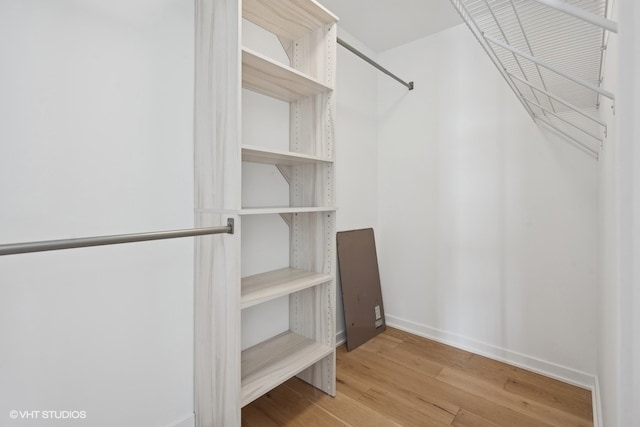 walk in closet with light hardwood / wood-style floors