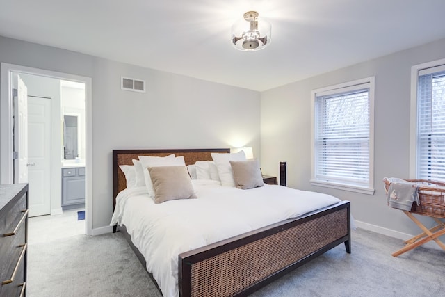 bedroom with light colored carpet and ensuite bath