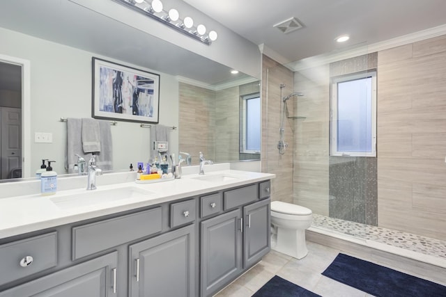 bathroom with a tile shower, toilet, vanity, and ornamental molding