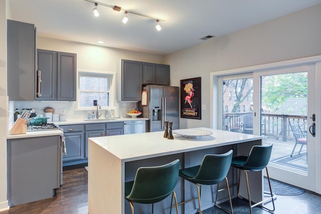 kitchen with decorative backsplash, stainless steel appliances, a kitchen island, and a wealth of natural light