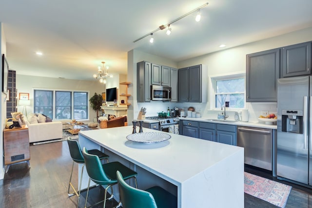 kitchen featuring sink, dark hardwood / wood-style floors, a kitchen island, stainless steel appliances, and a chandelier