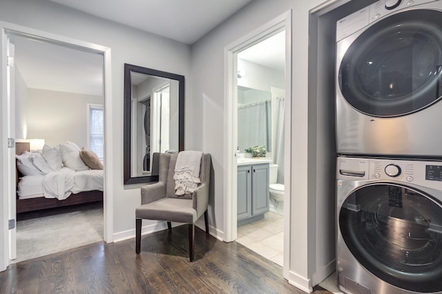 clothes washing area with stacked washer and dryer and dark wood-type flooring