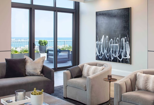 living room with plenty of natural light, floor to ceiling windows, a water view, and wood-type flooring