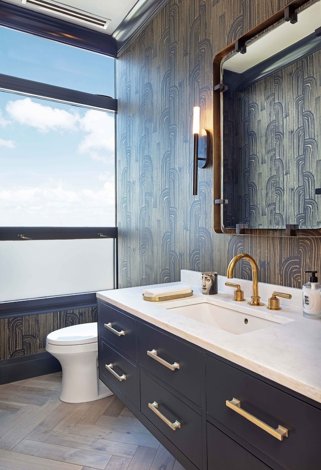 bathroom with toilet, vanity, and parquet flooring