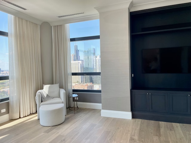 living area featuring light hardwood / wood-style floors and ornamental molding