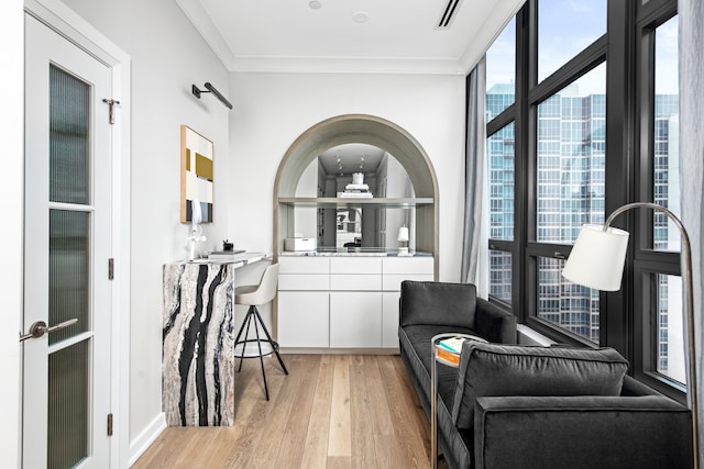 living area with light hardwood / wood-style floors, plenty of natural light, and crown molding