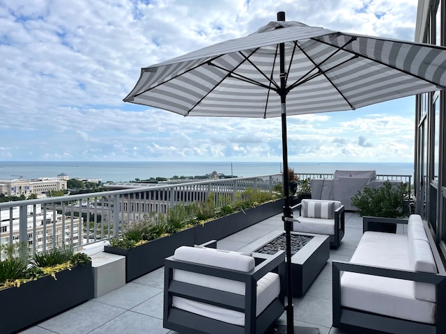 view of patio with a water view and an outdoor living space with a fire pit