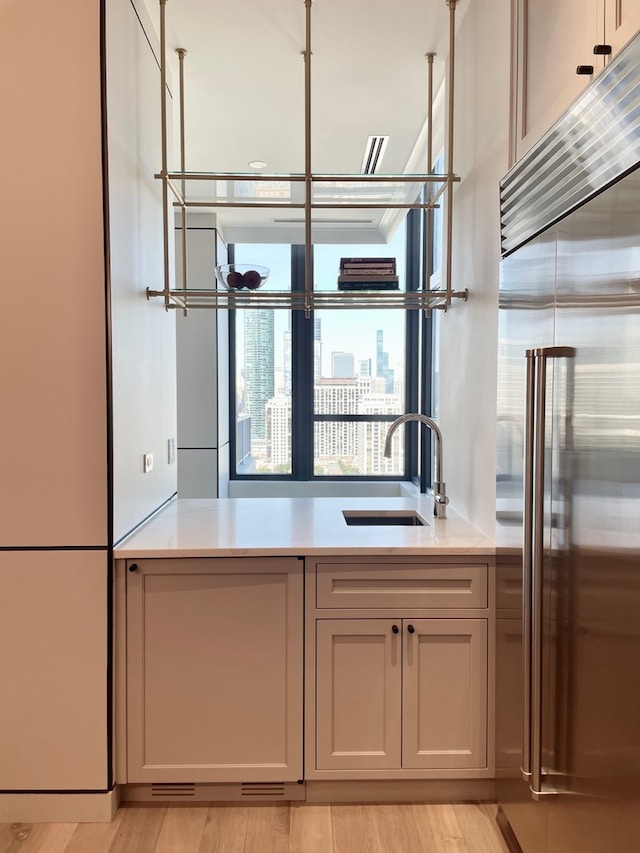 kitchen with built in fridge, sink, and light hardwood / wood-style flooring