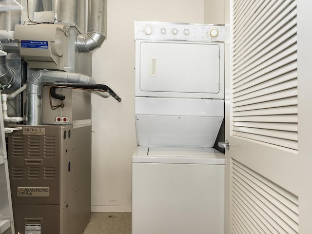 clothes washing area with heating unit and stacked washer and dryer