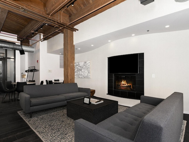 living room featuring a tiled fireplace, a towering ceiling, beamed ceiling, and wooden ceiling