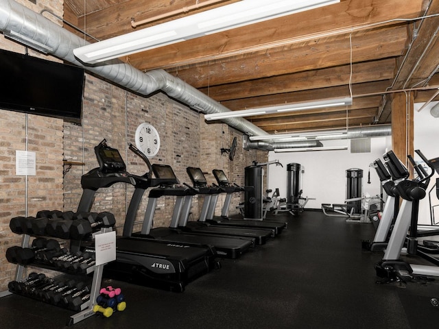 workout area featuring brick wall